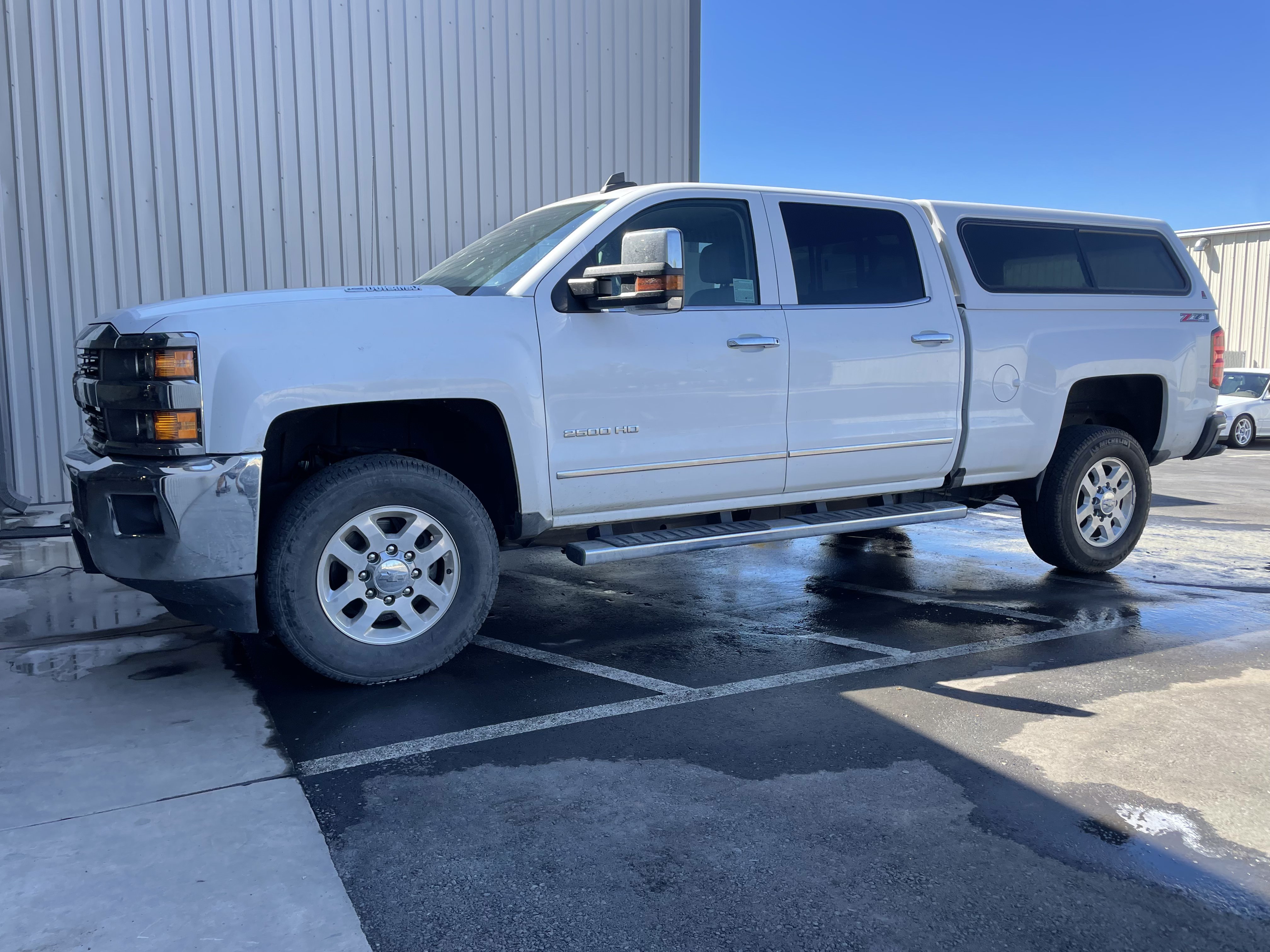 White work truck before exterior detailing with road film on the paint and wheels.